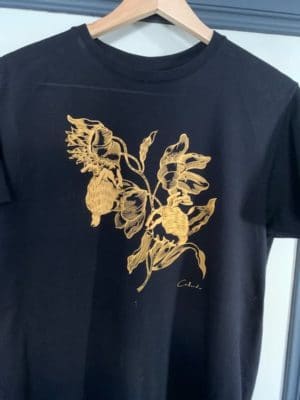 T-Shirt noir au motif jaune orangé. Paradis de l'artiste contemporain Philippe Caillaud